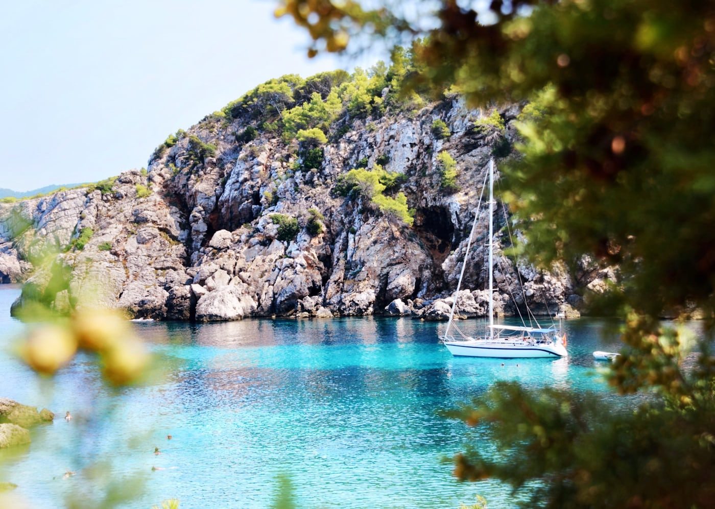 Verborgen baai met zeilboot en turquoise water op Ibiza — IbizaLuxeHuur